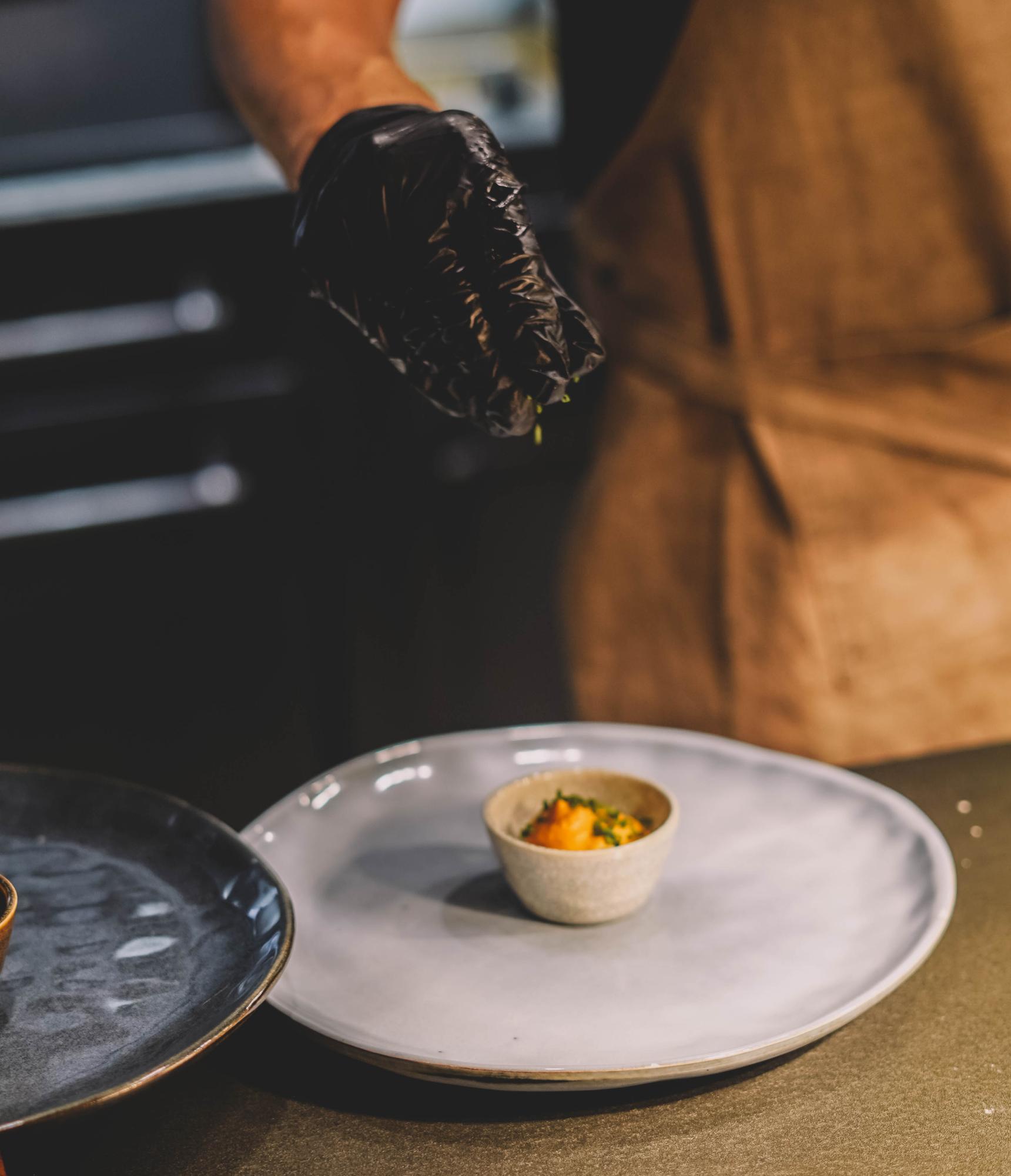 Chef plating a seasonal dish on a white plate